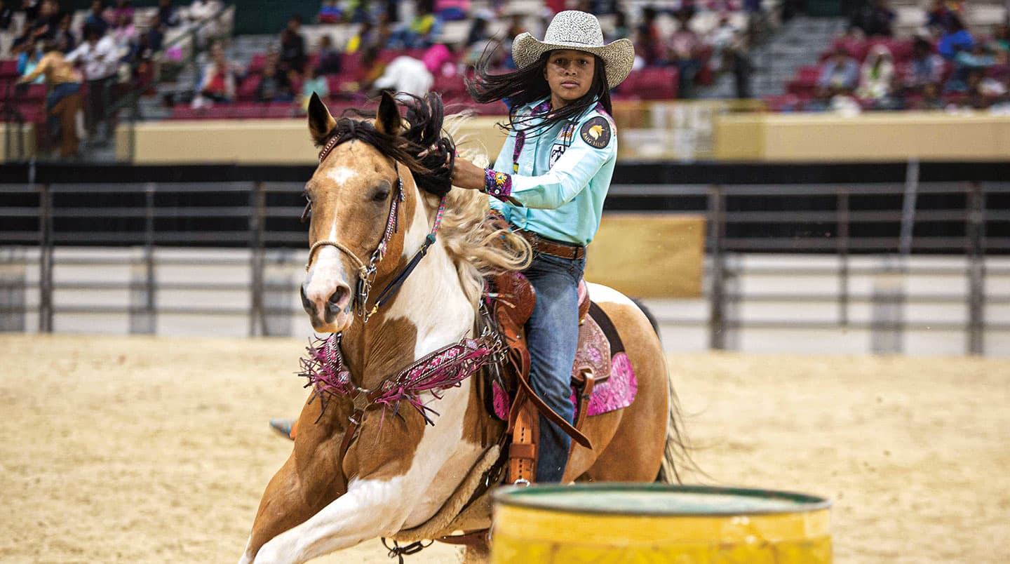 young cowgirl riding a horse during a competition