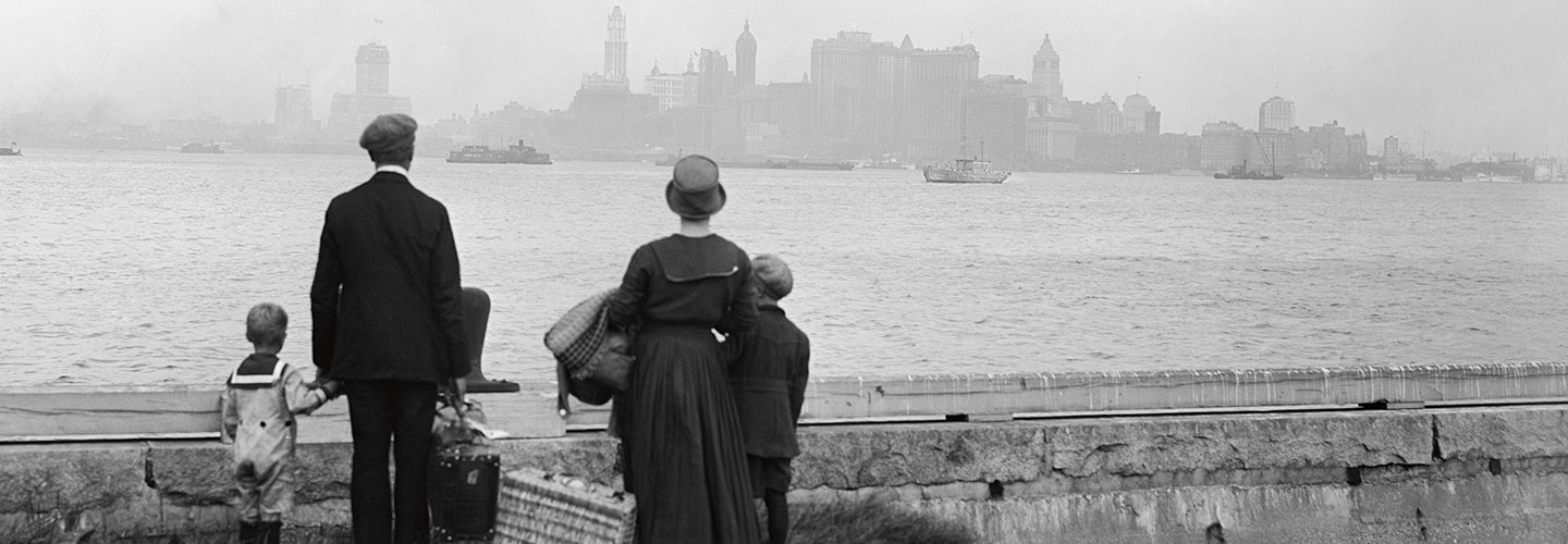 A family carries their belongings as they look across the bay at New York City.