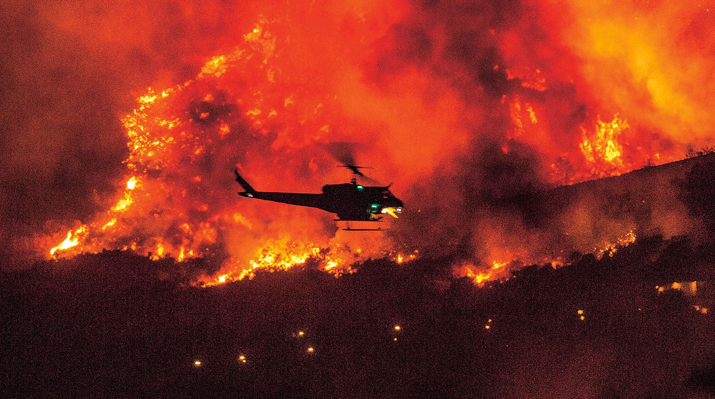 A helicopter flies above a fire