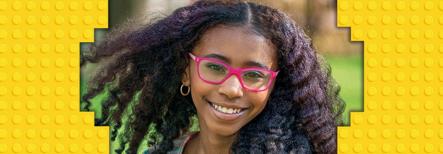 A girl with long curly unbraided hair and pink glasses
