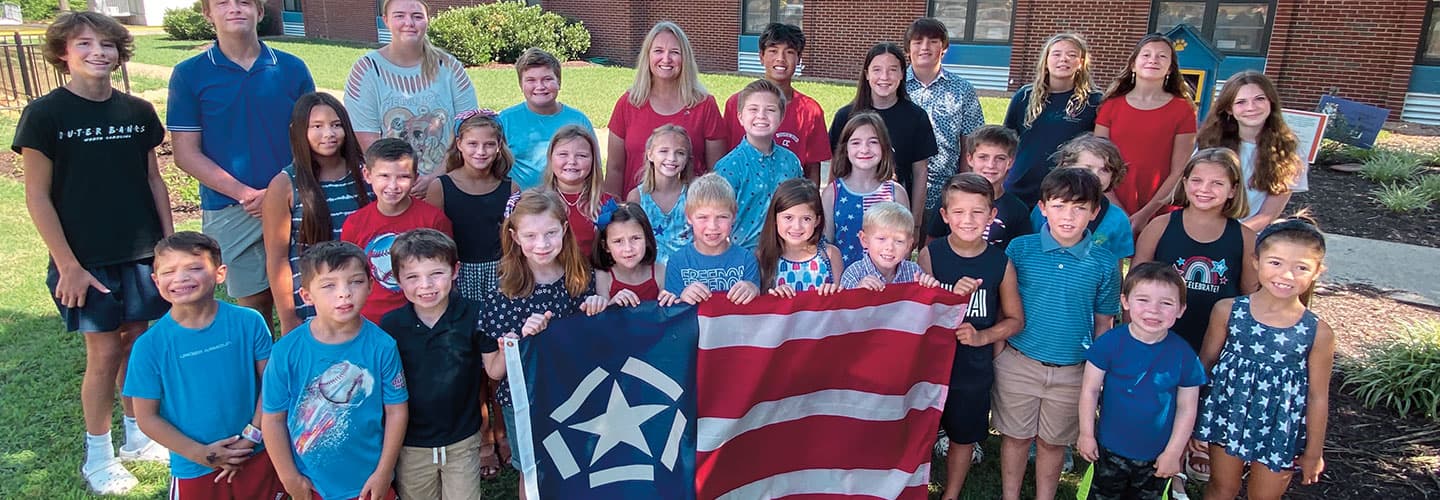 A large group of people holding a patriotic flag while posing for a photo