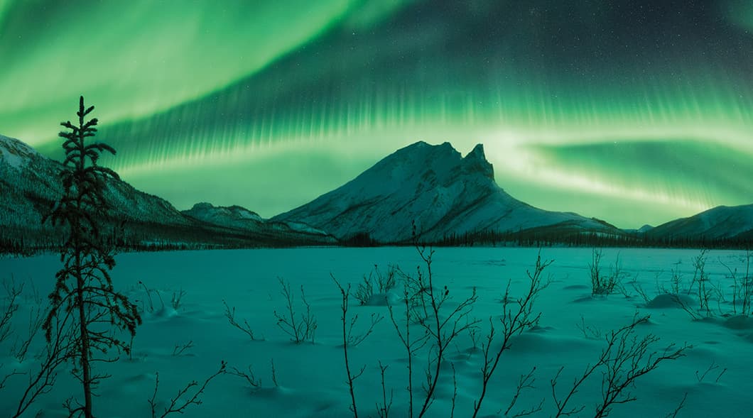 Photo of Northern Lights in a snowy mountain landscape
