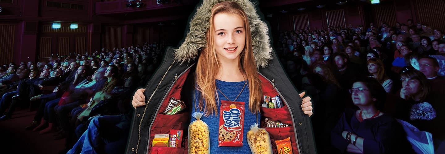 Image of a kid wearing a coat full of snacks in a movie theatre