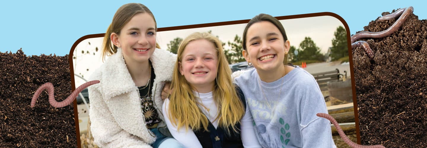 Image of three friends posing for photo against backdrop of dirt and worms