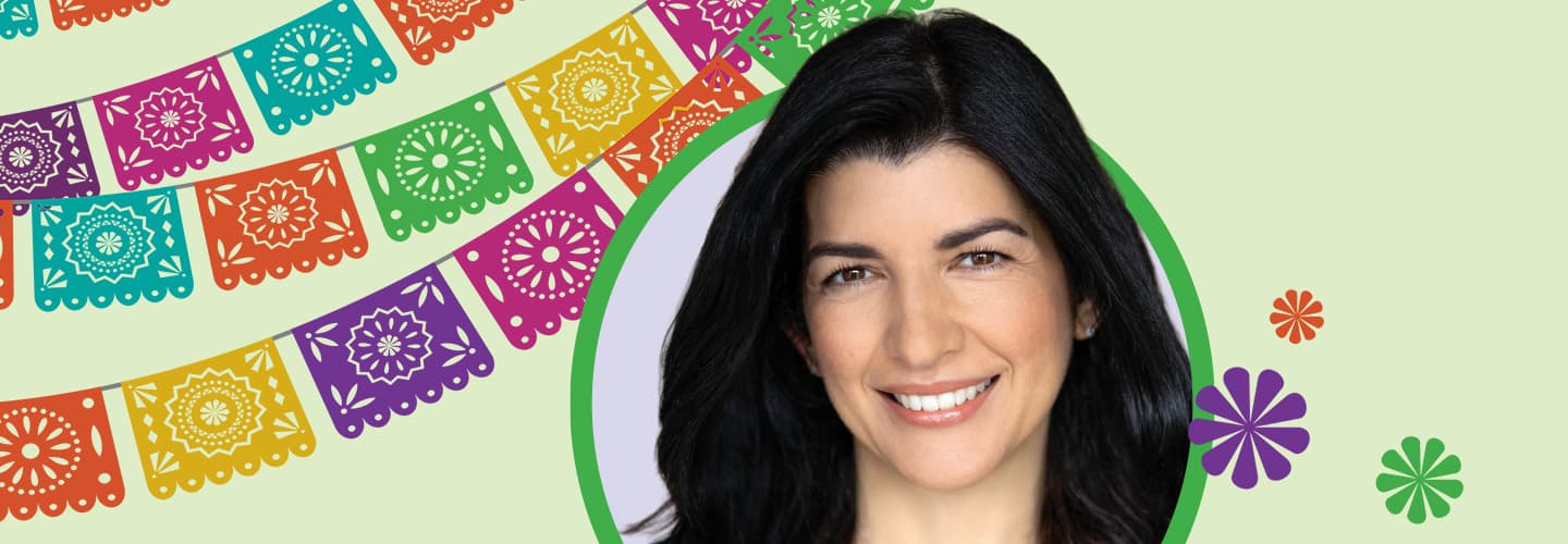 A woman faces forward beside colorful papel picado banner decorations