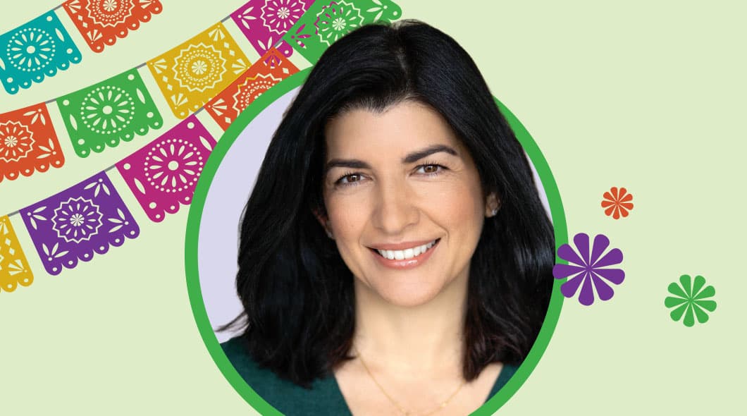 A woman smiles in a portrait framed by colorful papel picado banners and floral decorations