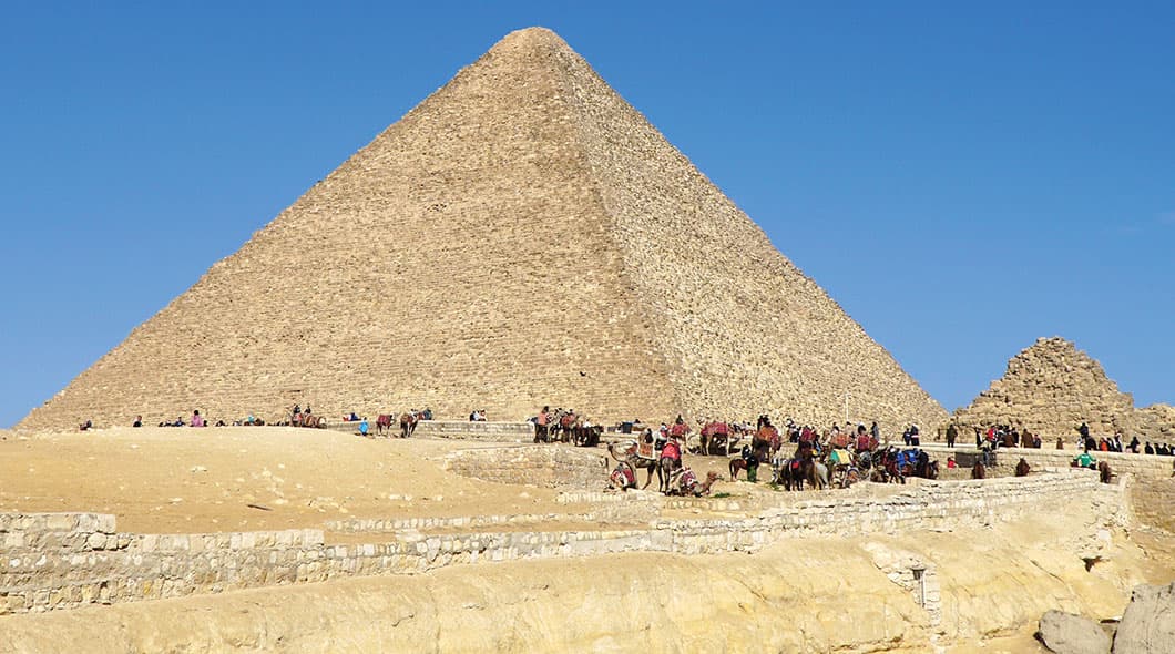 The Great Pyramid of Giza with camels and visitors gathered at its base