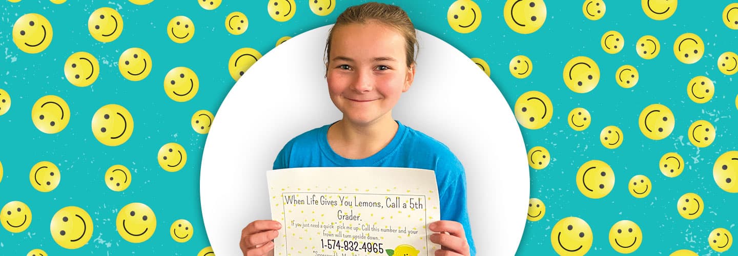 Student posing with a certificate in front of a smiley face background